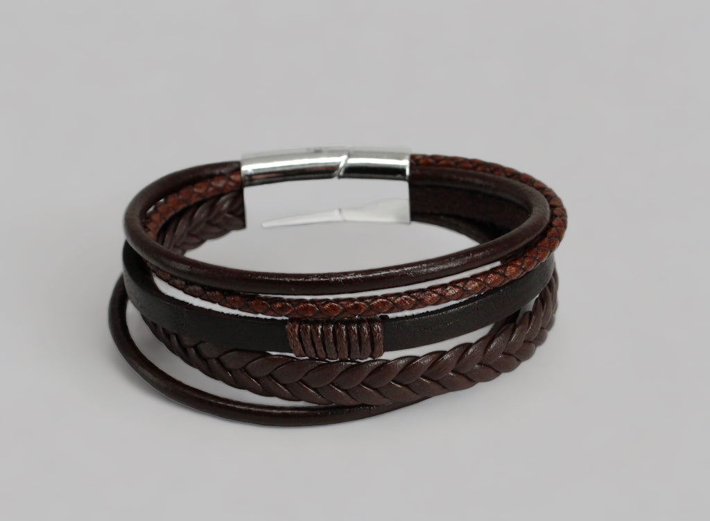 Gevlochten bruin leren heren armband met zilverkleurige magnetische sluiting. Upgrade je stijl met deze schitterende armband die de perfecte balans tussen klassiek en eigentijds creëert. Verkrijgbaar bij Optiwatch