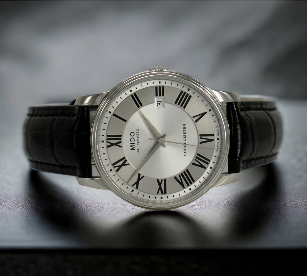 De Mido Baroncelli Chronometer Automatic heeft een zilverkleurige wijzerplaat, een zwarte leren band en Zwitserse precisiebeweging. Verkrijgbaar bij Optiwatch